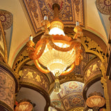 Decorative chandelier hanging from a ornate ceiling with intricate designs included .
