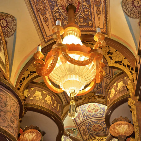 Decorative chandelier hanging from a ornate ceiling with intricate designs included .