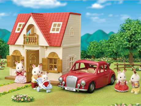 Toy house with red roof, toy Family Cruising Car, and toy figures in a garden setting
