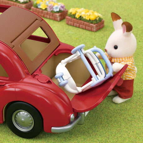 Red toy Family Cruising Car with a baby buggy and a rabbit figure standing next to it on a grassy background.