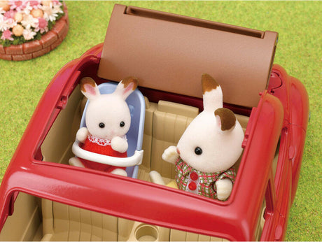 Two toy rabbits in a red Family Cruising Car with an open top on a grassy background