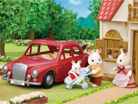 Toy family with a red Family Cruising Car in front of a house with a garden.