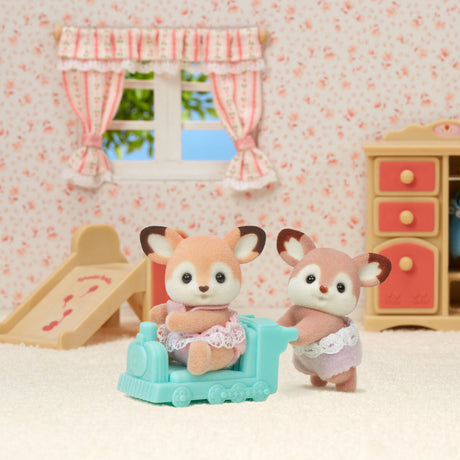Calico Critters - Deer Twins figures in a miniature room with floral wallpaper and furniture.