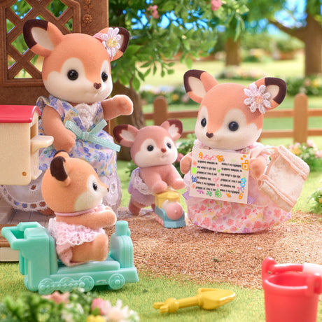 Toy deer family with a baby and accessories in a garden setting