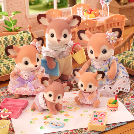 Set of toy deer figures with accessories on a table in a room setting.
