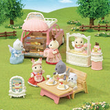 Toy set with animal characters around a Calico Critters - Village Cake Shop Starter Set in a grassy outdoor setting.