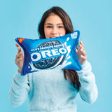 Person holding a blue Oreo pillow against a light blue background