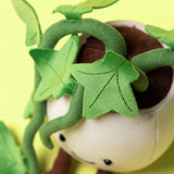 Close-up of Amuseables Ivy plush toy showing green fabric ivy leaves and stems wrapped around soft beige and brown body against yellow background