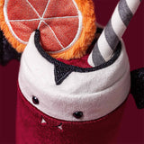 A close-up of a plush Amuseables Vampop Drink, featuring a red velvet-like body, white plush whipped cream top, black glitter trim, a striped gray-and-white straw, and an orange slice accent on a dark red background.