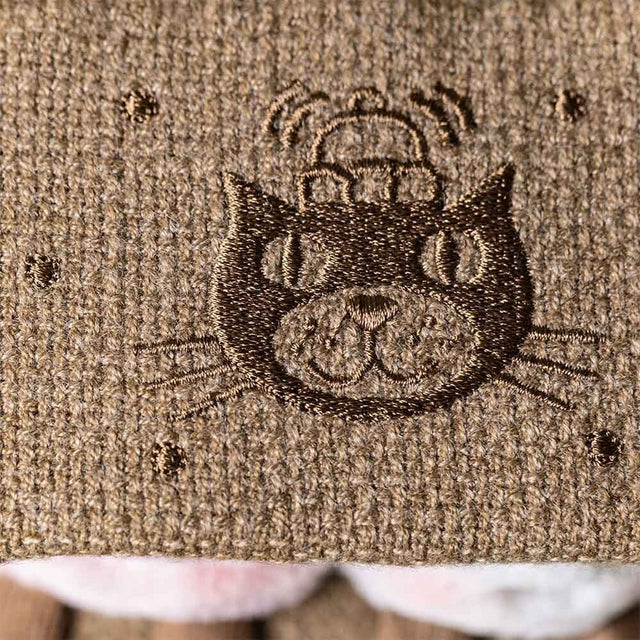 Embroidered cat design on a textured fabric surface