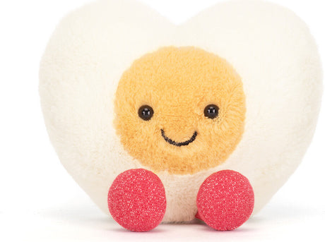 Amuseables Heart Boiled Egg plush toy featuring a smiling yellow yolk face, soft white heart-shaped egg white, and two small red feet, perfect as a kid's birthday gift.