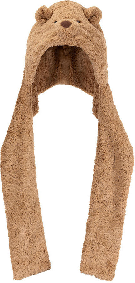 A plush Bartholomew Bear Bundlesnug hooded scarf in a warm tan-brown color, featuring embroidered bear eyes and nose on the hood and long hanging ear flaps, shown against a plain white background.