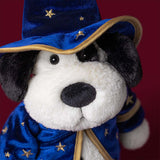 A plush Rufferty Puppy Wizard Outfit toy dressed as a wizard, wearing a blue velvet hat and matching robe with gold star details, photographed against a dark red background.