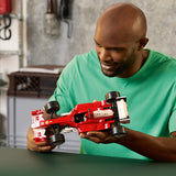 Man holding a red LEGO Icons: Ferrari F2004 & Michael Schumacher model in a casual setting