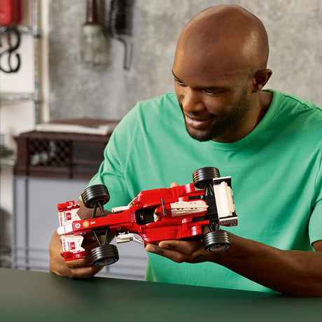 Man holding a red LEGO Icons: Ferrari F2004 & Michael Schumacher model in a casual setting