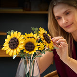 Woman placing a bouquet of LEGO Botanicals: Sunflower Bouquet in a clear vase.