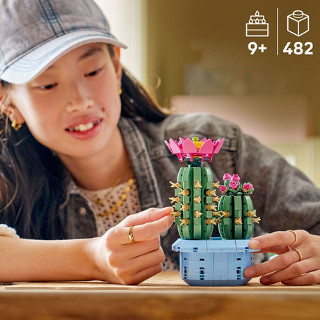 Child playing with a LEGO cactus set on a wooden table