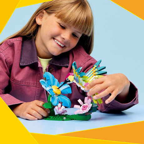 Child playing with colorful LEGO Creator: Wild Animals: Colorful Hummingbird set on a blue background