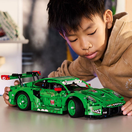 Child playing with a LEGO Technic: Porsche 911 GT3 R REXY AO Racing Car