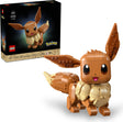 LEGO toy building set showing a constructed Eevee figure in front of its retail box on a clean white background. The set includes the assembled brown and cream Eevee model with large expressive eyes and raised ears, plus the black product box featuring the LEGO and Pokémon branding and the built toy pictured on the packaging.
