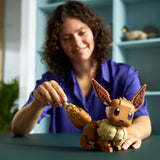 Woman playing with aLEGO Pokémon Eevee on a table.