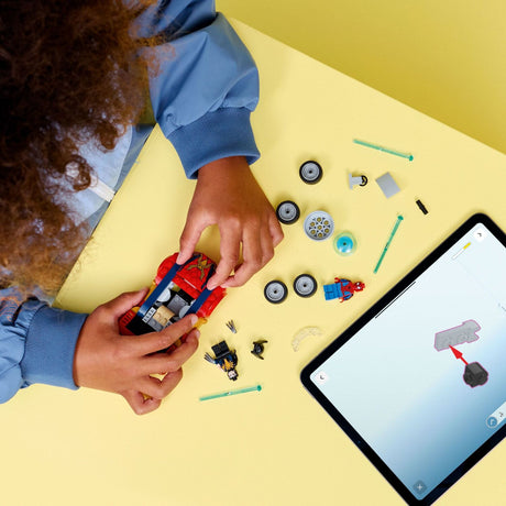 Child playing with LEGO Super Heroes Marvel: Spider-Man Car vs. Venomized Wolverine kit on a yellow table with a tablet displaying a design.