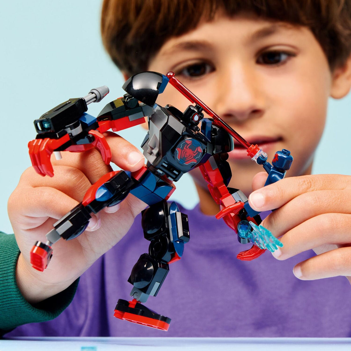 Child holding a LEGO Super Heroes Marvel: Miles Morales Mech vs. Spider-Man 2099