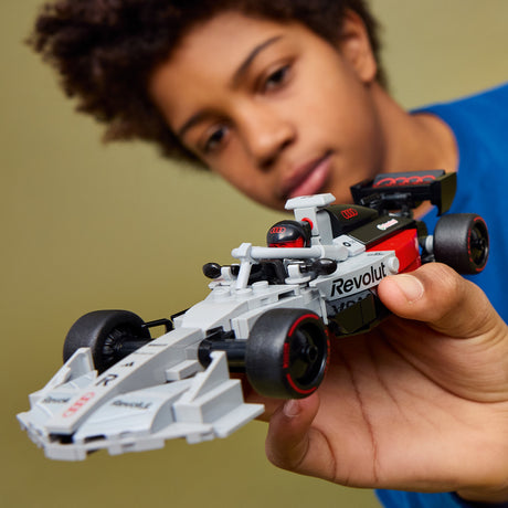Person holding a toy Lego Formula 1 car with 'Revolution' branding.
