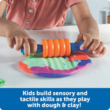 Child playing with a colorful dough roller and mold on a white surface.