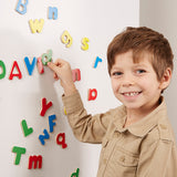 Child playing with colorful magnetic letters on a white board