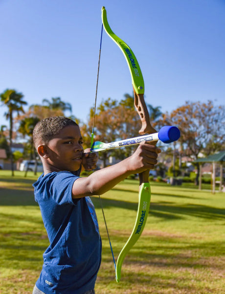 Child holding a Faux Bow Protege and arrow outdoors on a sunny day.
