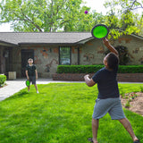 Two children playing with Koosh® Paddle Play Set in a backyard with a house in the background.