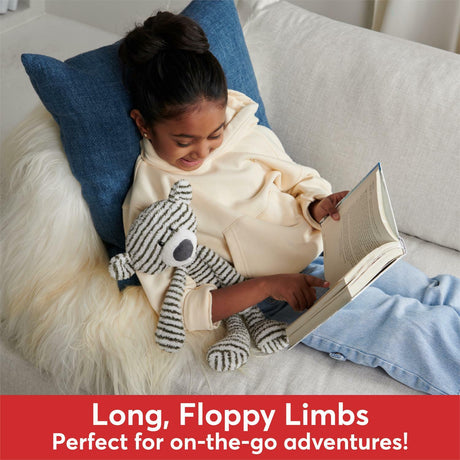 Person sitting on a couch with a book and plush Stripe Toothpick Bear - 15 In toy, surrounded by pillows.