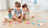 Two children playing with Dress-Up Magnetic Puzzle wooden dolls and colorful pieces on a light-colored floor.