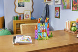 Colorful Magna-Tiles microMags Travel Deluxe 55 Piece Set on a wooden table with a child's room in the background.