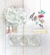 Set of clear silicone molds, bottles, and floral decorations for Wish*Craft Flower Power DIY Soap kit on a light wooden surface