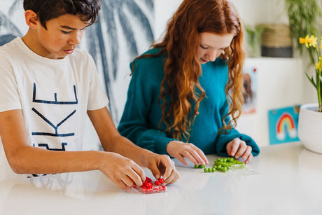 Two children playing with IQ MINI Puzzle Game toys on a table indoors.
