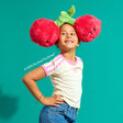 Child wearing a plush toy Mini Squishable Comfort Food Cherries on a teal background
