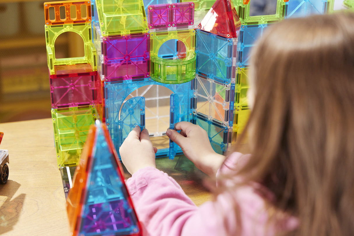 Child playing with colorful Magna-Tiles City Center 110 Piece  on a wooden table