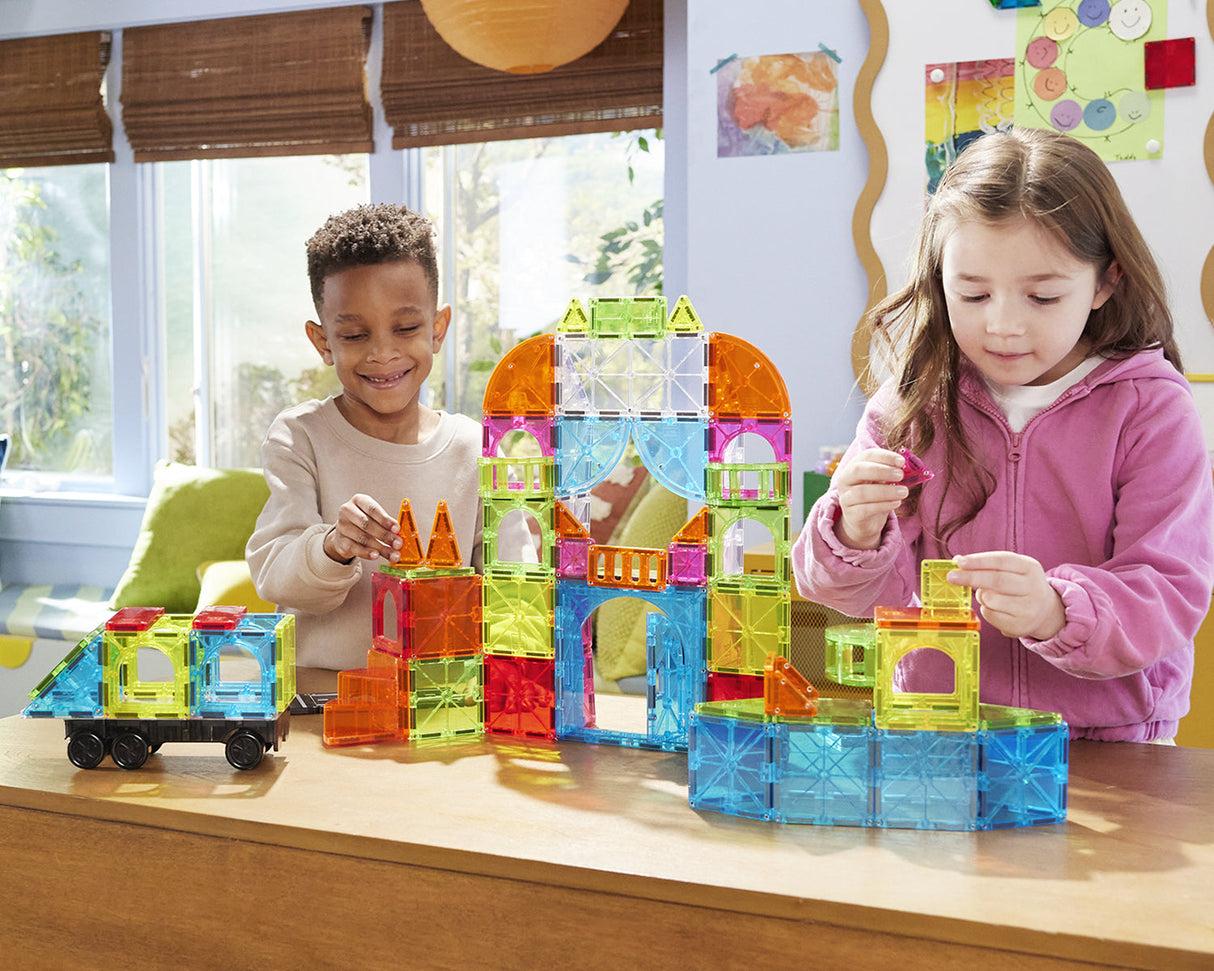Two children playing with colorful Magna-Tiles City Center 110 Piece Set on a table.