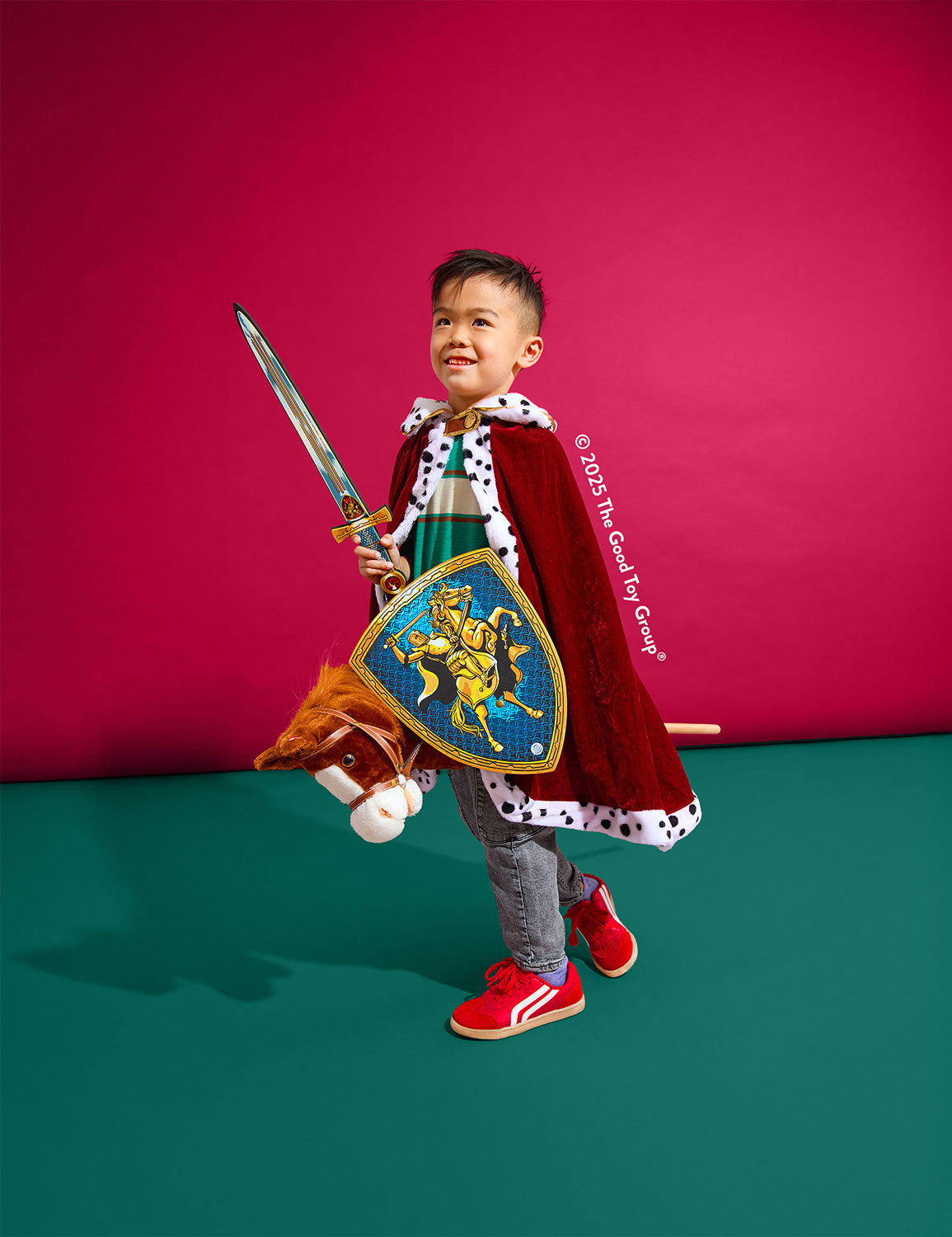 Child in a knight costume with a sword and shield against a pink and green background