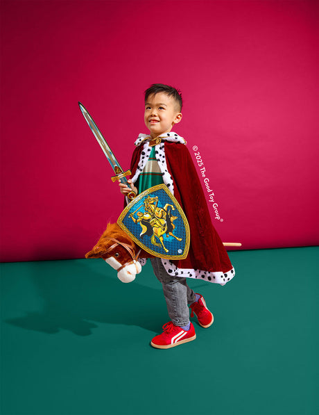 Child in a knight costume with a sword and shield against a pink and green background