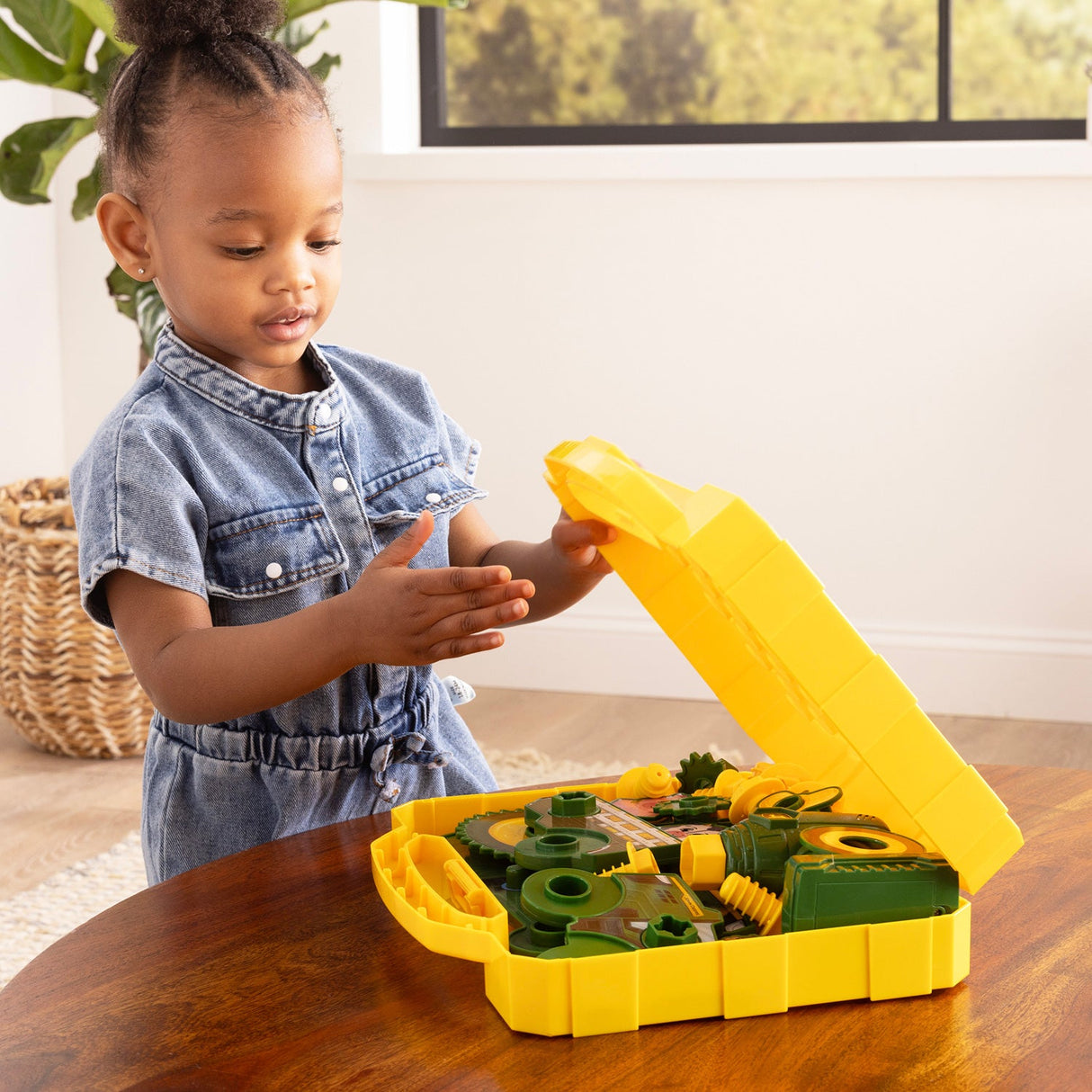 Child playing with John Deere Build-A-Buddy Activity Board on a wooden table