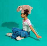 Child with a Pygmy Hippo Super Soft toy on their head against a teal background