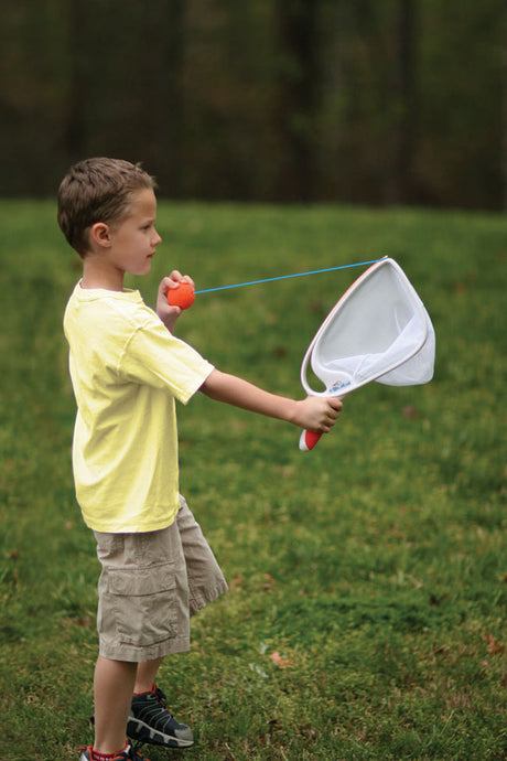 Child holding a Djubi SlingBall Classic in a grassy field