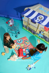 Two children playing with toys in front of a Bluey Camping Activity Fort.