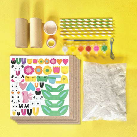 Craft supplies for Paper Mache All Day! including stickers, paper, straws, and paint on a yellow background