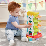 Child playing with a Kidoozie Drop 'n Roll Activity Tower on a carpeted floor.