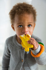 Child holding a Oli & Carol Ana Banana Teether with a white background