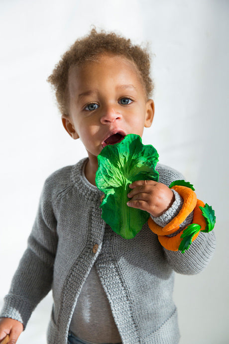 Child holding Oli & Carol Kendall the Kale Teether against a plain background